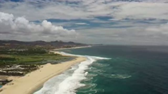 LOS CABOS MEXICO-2020: Ocean Waves Hitting A Beach With Plants Covered Dunes