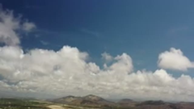 LOS CABOS MEXICO-2020: Puffy White Clouds Move Slowly Over Mountainous Terrain