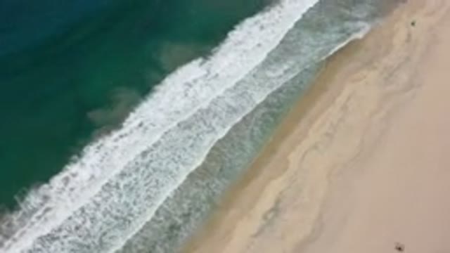 LOS CABOS MEXICO-2020: Gentle Blue Waves Crashing Onto The Sandy Smooth Shore