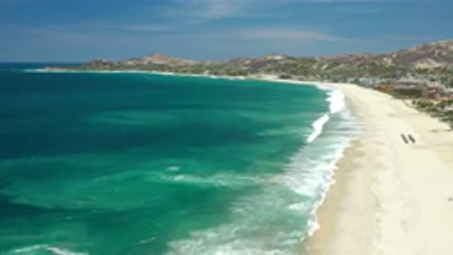 LOS CABOS MEXICO-2020: Waves Come Ashore On A Sandy Beach At An Ocean Inlet