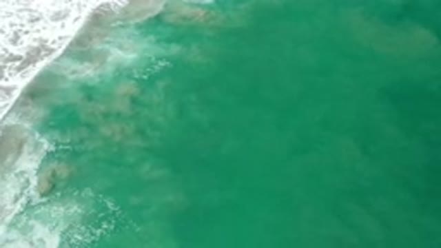 LOS CABOS MEXICO-2020: Waves Of Green Water Crash On The Beach Mixing Seafoam