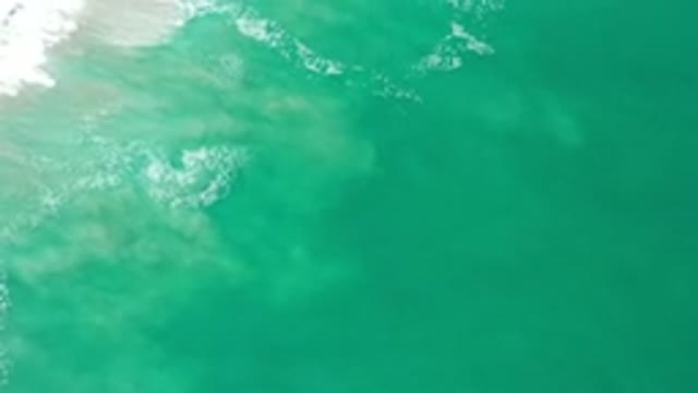 LOS CABOS MEXICO-2020: Green Ocean Water Rolling In Tide Into Sandy Beach
