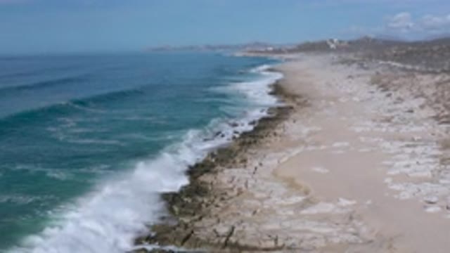 LOS CABOS MEXICO-2020: Clear Blue Waves Crash On Beach With Bright Blue Skies