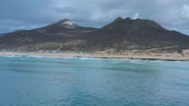 LOS CABOS MEXICO-2020: Island Beach Next To Huge Volcano Under A Gray Dark Sky