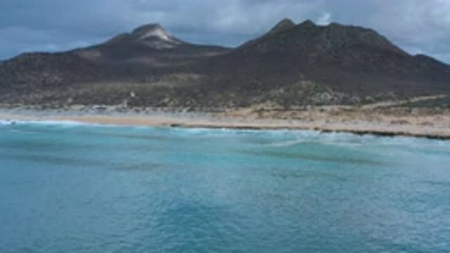 LOS CABOS MEXICO-2020: The Ocean Waves Hitting The Shore With Mountains In The