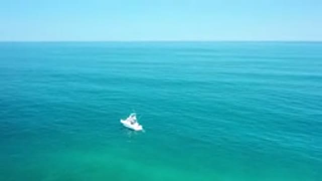 LOS CABOS MEXICO-2020: White Boat Floating On Green Ocean Spanning Out To Horizon