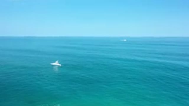 LOS CABOS MEXICO-2020: White Yacht Sailing In Turquoise Water With A Speedboat