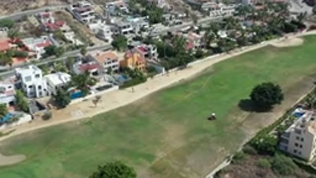 LOS CABOS MEXICO-2020: A Green Lawn Alongside A Residential Area With A Tractor