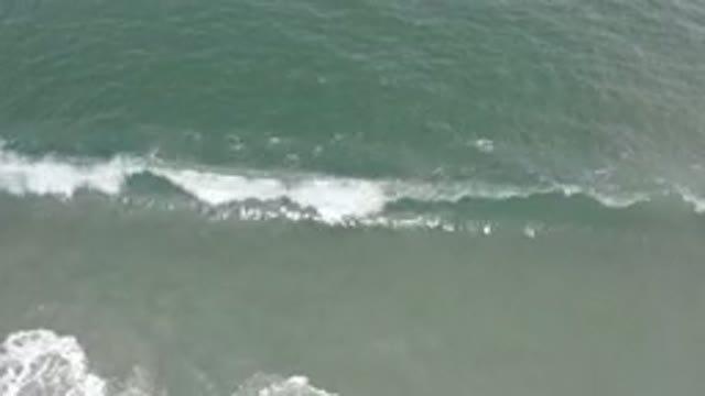 LOS CABOS MEXICO-2020: Wave Of Blue Green Water Crashes Into Sandy Beach With Ripples