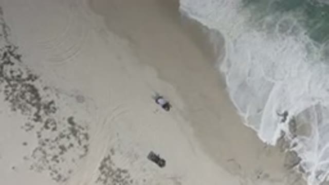LOS CABOS MEXICO-2020: A Drone Hovers Overhead Two Vehicles Parked On A Sandy