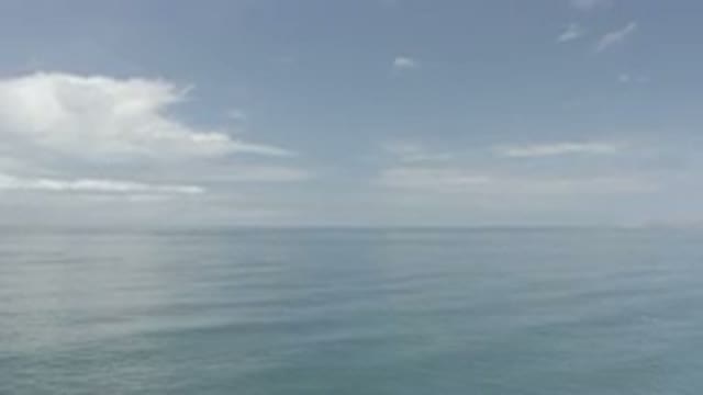 LOS CABOS MEXICO-2020: Camera Flying Over A Calm Ocean With Small White Clouds