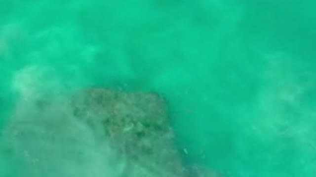 LOS CABOS MEXICO-2020: Sand Is Stirred Around A Rock Under The Clear Teal Waters