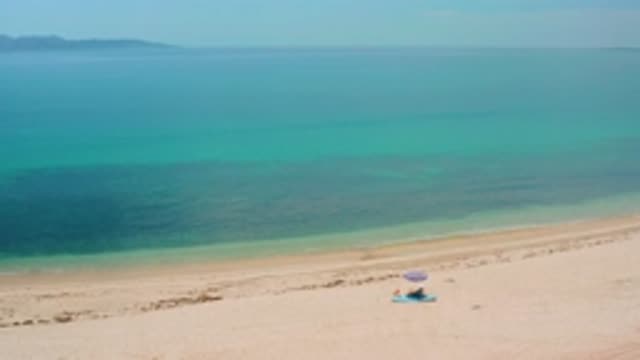 EL SARGENTO LA VENTANA MEXICO-2020: Person Sitting On A Towel Under A Blue Beach Umbrella