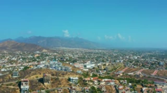 LOS CABOS MEXICO-2020: Flying Over Buildings In City With Mountains In The Distance