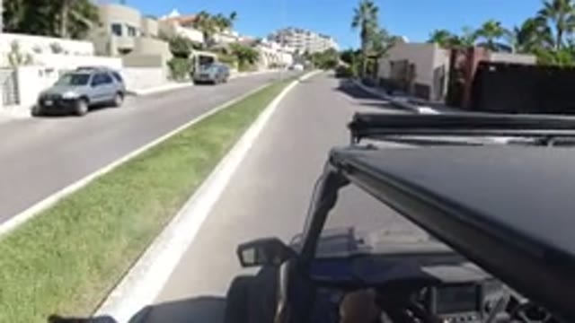 LOS CABOS MEXICO-2019: Car Driving Down A Street Surrounded By Homes And Palm Trees