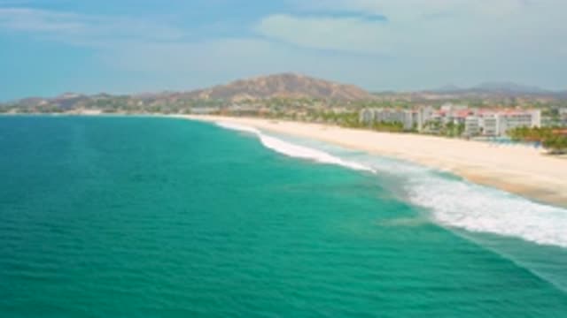 SAN JOSE DEL CABO MEXICO-2020: Tall Building Near The Shore With White Clouds And Vast Sky