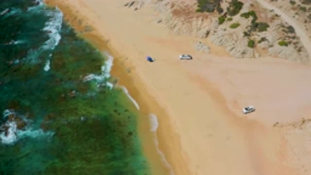 SHIPWRECKS BEACH BCS MEXICO-2020: Two Cars Parked On A Sandy Beach With Slow Rolling Waves
