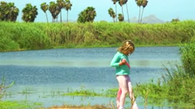 SAN JOSE DEL CABO MEXICO-2020: Cute Young Girl Holding Pink Cloth Walking Near River