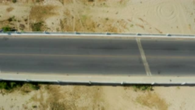 SAN JOSE DEL CABO MEXICO-2020: A Child Running Along a Concrete Road with a Blue Car Passing by