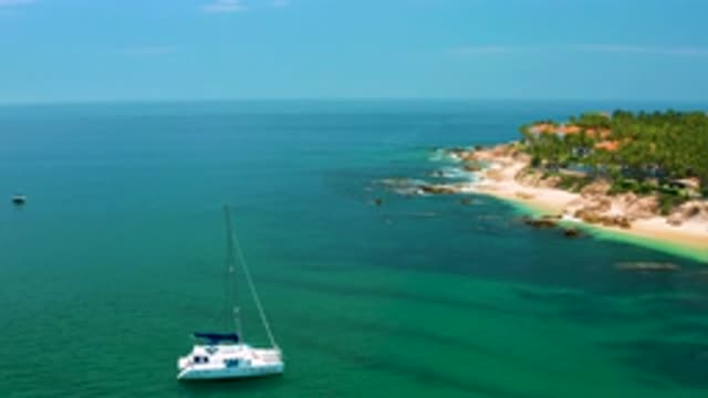 PALMILLA BEACH BCS MEXICO-2020: A Sailboat Is Going Across A Sea Next To A Rocky Shore