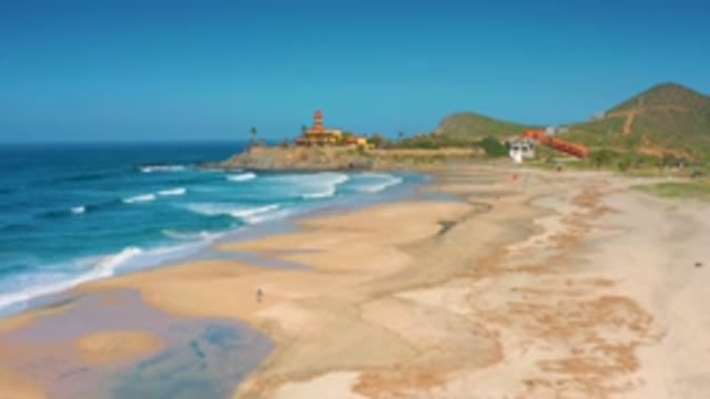 CERRITOS BCS MEXICO-2020: The Waves Wash The Shore While A Lighthouse Rises Over