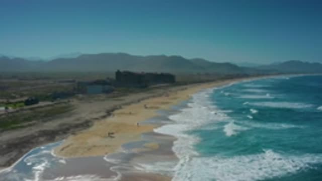 CERRITOS BCS MEXICO-2020: Waves Crashing On Sandy Beach With Dusky Mountains In