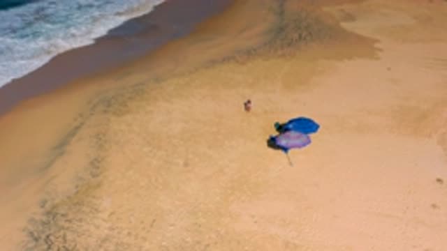 CERRITOS BCS MEXICO-2020: Child Runs To Family Sitting Beneath Purple And Blue Umbrellas