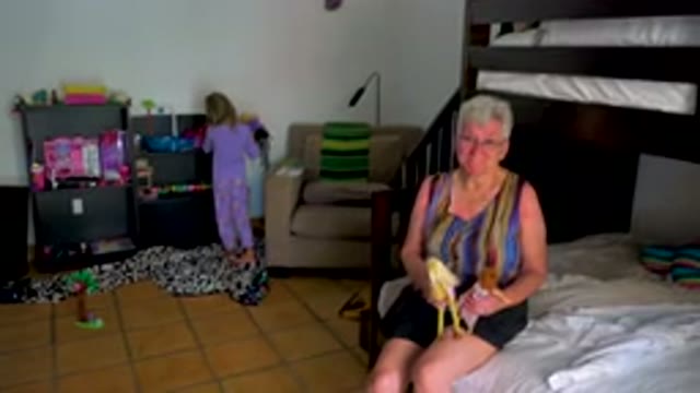 Grandmother And Child Playing With Dolls In Bedroom