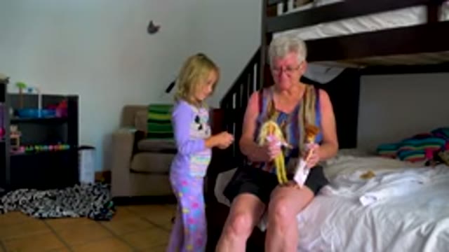 Grandmother And Granddaughter Playing With Dolls