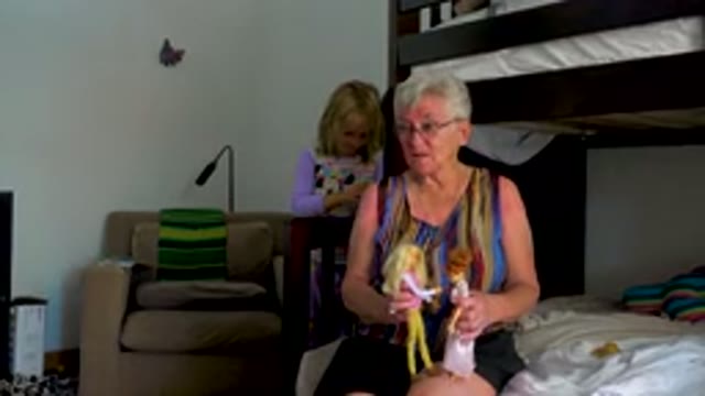 Grandmother Playing With Dolls On Bed