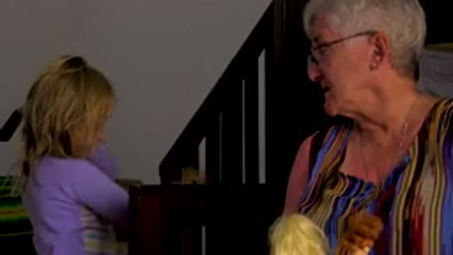 Grandmother And Granddaughter Playing With Dolls