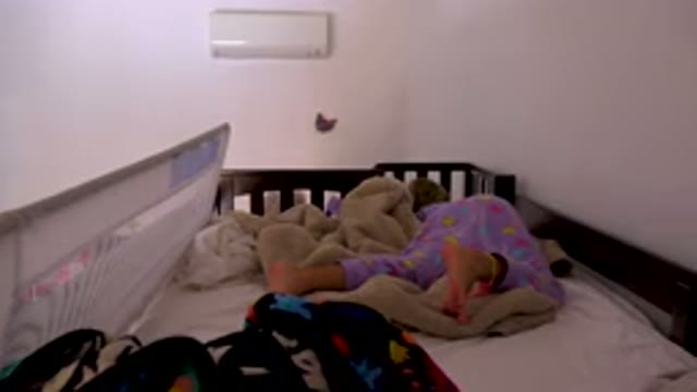 Child Sleeping Restlessly In Bed With Safety Rail