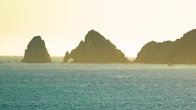 CABO SAN LUCAS MEXICO C-2020: Boat Passes By A Set Of Three Cliffs In Calm Water