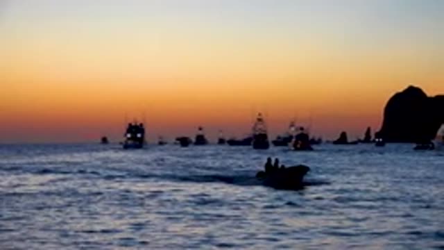 CABO SAN LUCAS MEXICO-2020: Streamer Boat Running at Dusk with Yellowish Red Sky