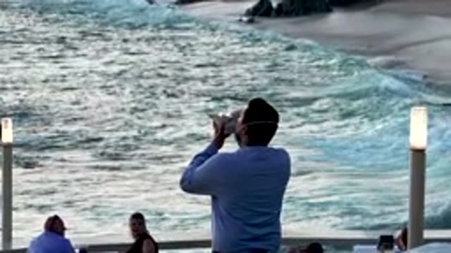 CABO SAN LUCAS MEXICO-2020: Man Playing Mouth Instrument Near The Water