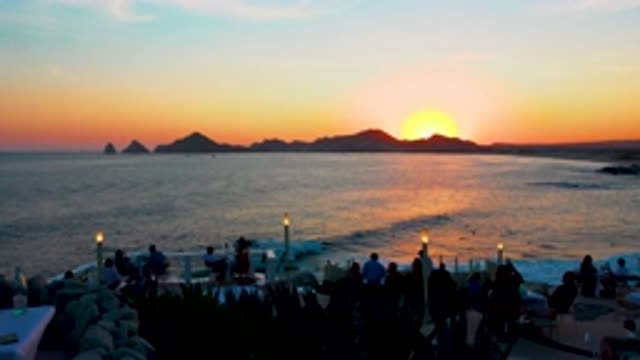 CABO SAN LUCAS MEXICO-2020: View Of An Island Coast With The Sun Setting And A Group Holding Torches